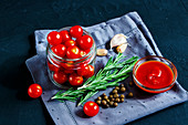 Close up of healthy ingredients for cooking cherry tomato sauce on dark rustic background