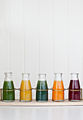 A tray holding individual jars of fresh pressed juices (green spinach, lemon ginger, spirulina, orange carrot turmeric, and beet)