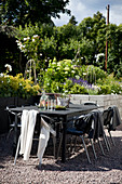 Table and chairs in courtyard with flowering plants in raised beds