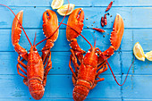 Two cooked lobsters with lemon wedges