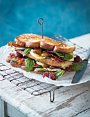 A toasted sandwich with grapes, crispy bacon, camembert and basil