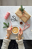 Frau mit Tasse Kaffee auf Marmortisch mit Weihnachtsdeko