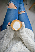Sitzende Frau hält eine Tasse Cappuccino