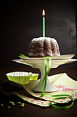 A mini chocolate cake with a candle on a cake stand