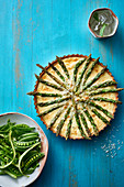 Asparagus tart with grated cheese springled across the top and served with fresh garden peas