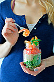 A woman holding a jar with a healthy shrimp salad