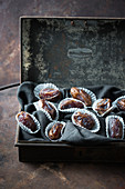 Medjool dates in paper cases and a metal tin