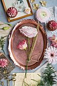Pink flowers, copper tray, vintage cards and cupcakes on grey surface