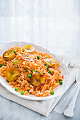 A plate with traditional mexican red rice (arroz rojo) with peas and fried plantains