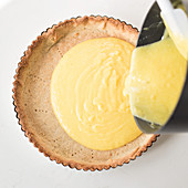 Making a lemon tart: pour lemon cream over shortcrust pastry
