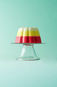 A trifle jelly on a gl;ass cake stand on a green background