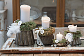 Advent arrangement of four candles and moss on old cake tins