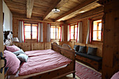 Doppelbett mit rot-weiß karierter Bettwäsche in einer Holzhütte