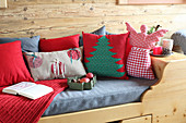 Holzbett mit weihnachtlichen Kissen und Engelsfigur in einer Holzhütte