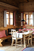 Festively decorated dining table and bench in log cabin