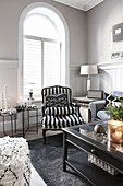 Black-and-white striped armchair in front of arched window in living room