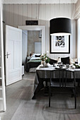 Set table in dining room in shades of grey with view into bedroom