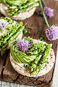 An avocado rose and blanched asparagus on rice crackers