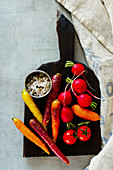 Top view of raw organic vegetables on dark rustic cutting board over grey background