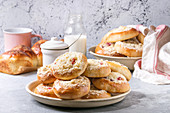 Traditional cottage cheese and srtawberry buns Moravsky colac in ceramic plate standing with bottle of milk on grey kitchen table