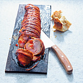 Grilled pork tenderloin wrapped in bacon, on a wooden plank