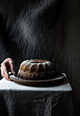 A woman dusting a vegan Bundt cake with icing sugar