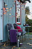 DIY fairy lights made from paper baking cases, a plaid and sheepskins on garden chairs