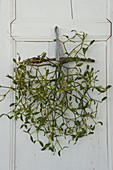 Branch of mistletoe hung from old cupboard door by gingham ribbon