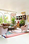 Wohnzimmer in Pastellfarben mit Glaswand zum mediterranen Garten