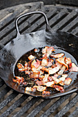 Grilled bacon with onions in an iron pan