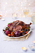 Roast duck with plums and roasted vegetables tomatoes carrots sweet potato and onions