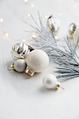 Christmas bauble decorations and white fir tree with Christmas lights