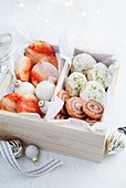 Orange biscuits with marbled orange icing, orange and chocolate pinwheel biscuits and lime and coconut shortbread biscuits all in a wooden gift box with tissue paper