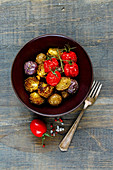 Oven-baked potatoes, Brussels sprouts and cherry tomatoes in a bowl