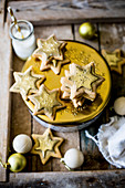 Festive star sugar cookies with golden royal icing and sprinkles on golden and white cookie tin for a gift