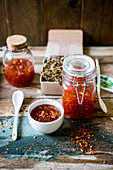 Festive sweet chili sauce in a jar with crackers served as a gift on a rustic wooden surface with a green name tag