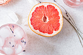 Halved grapefruit, dry lavender, and glasses of grapefruit, gin and lavender fizz with ice cubes