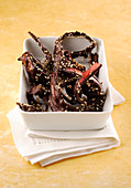Chocolate-covered red apple skins with sesame seeds
