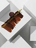 A chocolate praline on various chocolate textures with pistachios