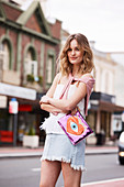 A young woman wearing a pink top and a frayed denim skirt