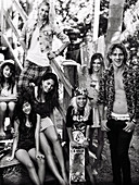 Young people and a kid with a skateboard at a beach house (black-and-white shot)
