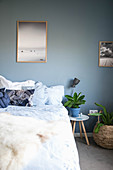 Double bed, houseplants and large photos in bedroom with blue-grey walls