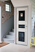 Door with chalkboard panels next to foot of staircase in foyer