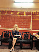 Blonde Frau in schwarzem Kostüm in chinesischem Ambiente