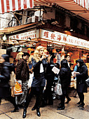 A young woman with a camera standing outside a Chinese restaurant in Hong Kong