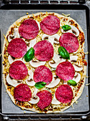 An unbaked salami and mushroom pizza