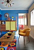 Ceramic bowls on coffee table, armchair and tall sideboard in living room with blue wall