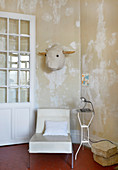 Stylised bull head on distressed wall above easy chair