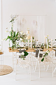Gedeckter Hochzeitstisch mit Frühlingsblumen, trockenen Zweigen und Cylinderkerzen, im Hintergrund Buffet mit Hochzeitstorte