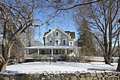 Grey wooden house with veranda in wintry garden